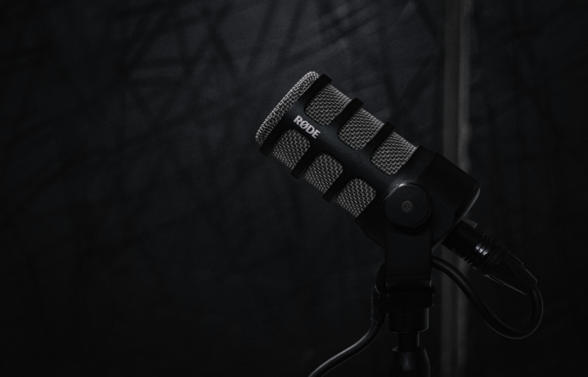 A close-up of a professional microphone on a stand against a dark background