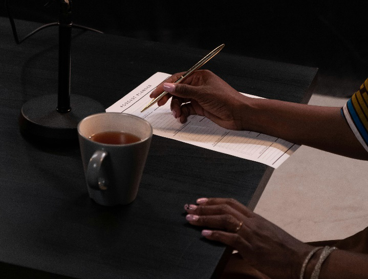 A person holding a pen and writing notes on a piece of paper.