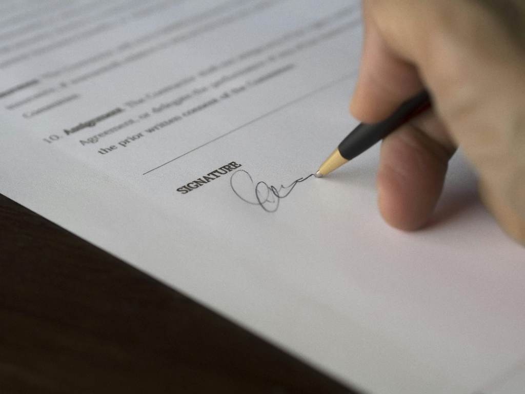 A person signing a contract with a pen