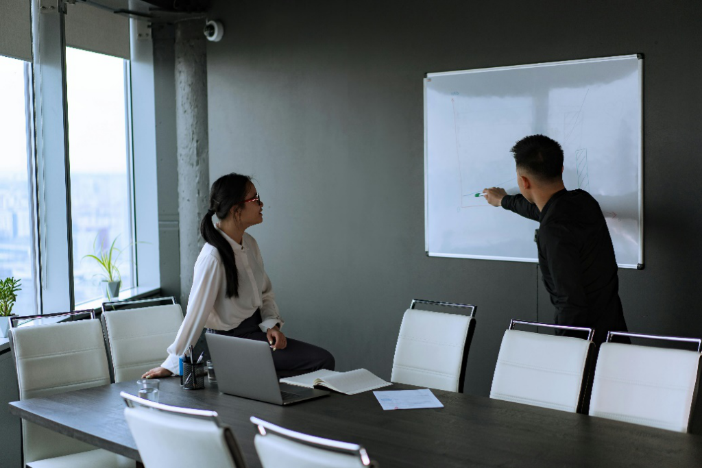 Two people standing in front of a whiteboard, brainstorming ideas