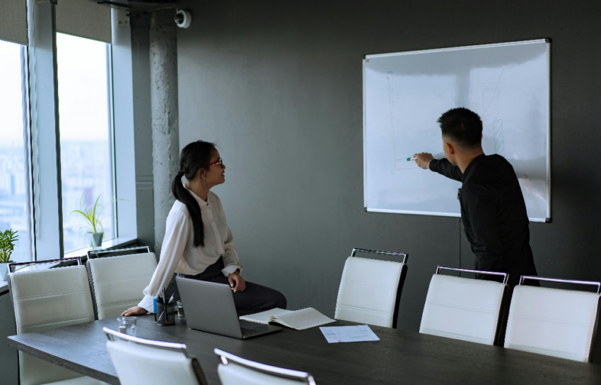 Two people standing in front of a whiteboard, brainstorming ideas