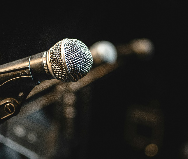 A close-up of a microphone on a stand, with a blurred background