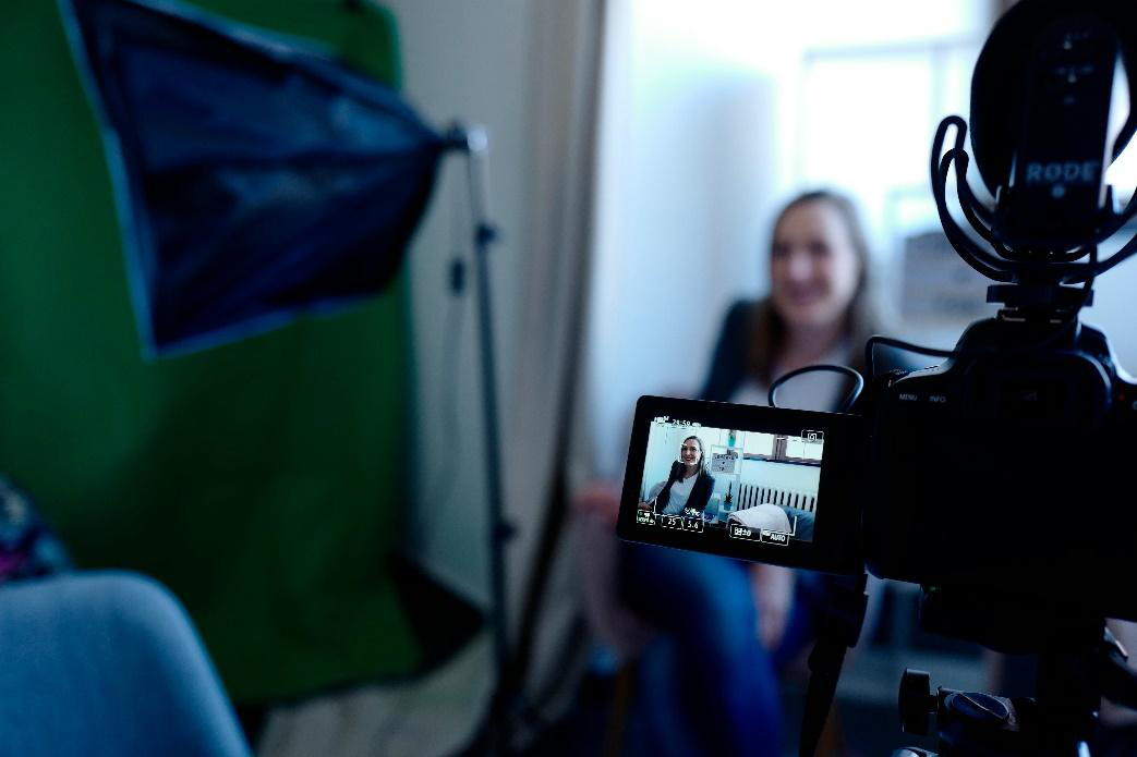 A close-up of a television screen showing a woman speaking during an interview