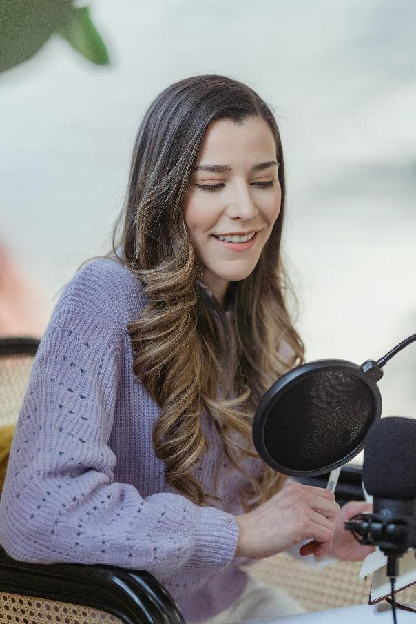 A woman speaking into a microphone during a podcast interview
