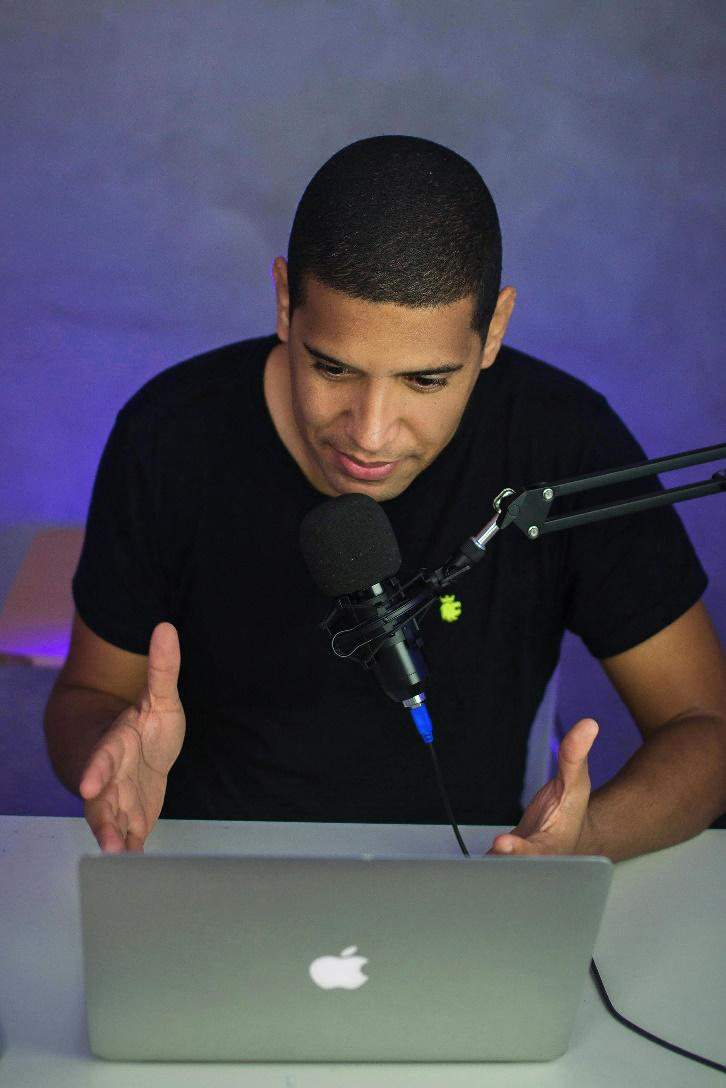 A man sitting in front of a laptop and a microphone