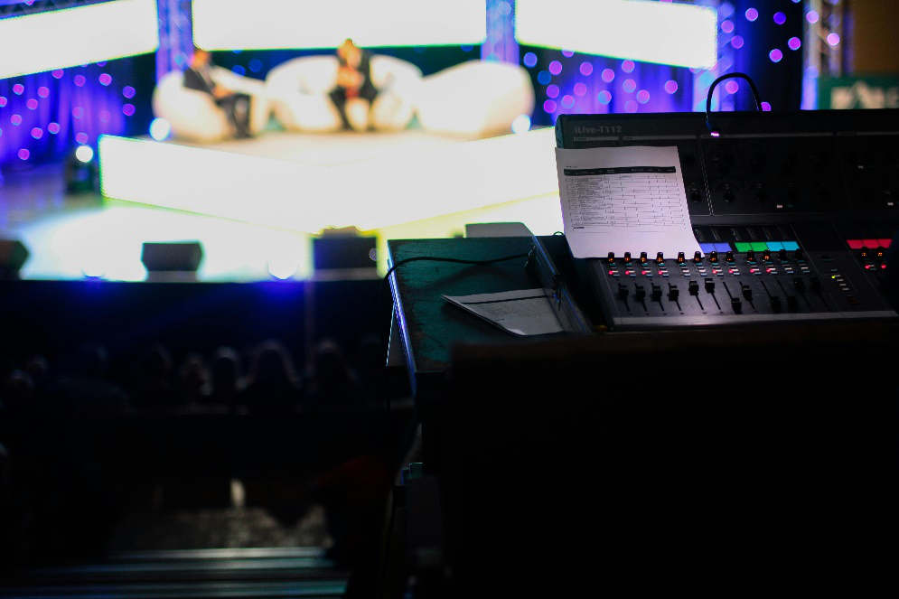A sound mixing board with a piece of paper sticking up, lit by a small light