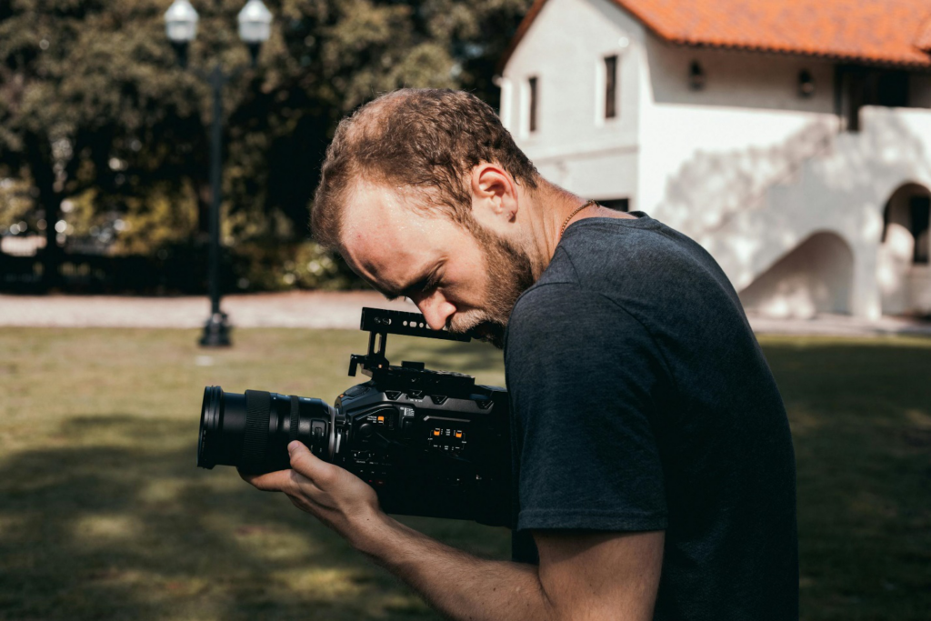 A man in a black crew neck t-shirt holding a black camera