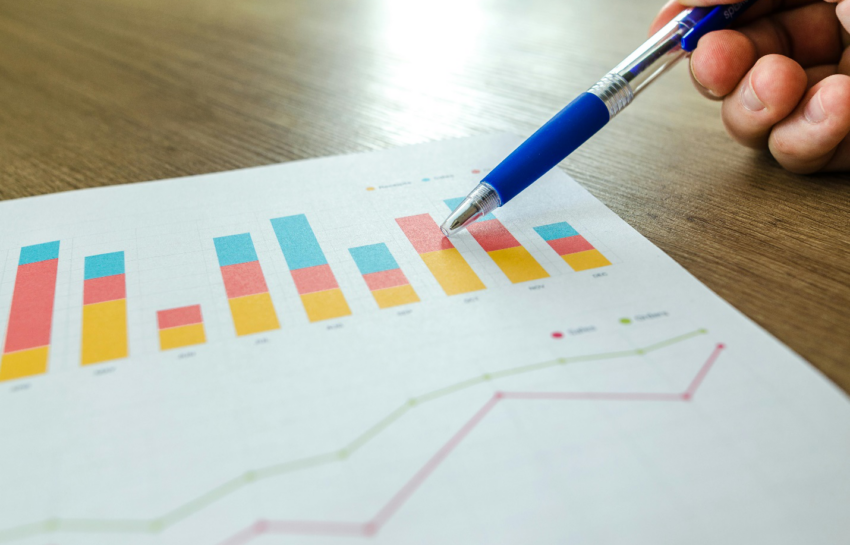 a person holding a pen and pointing at a graph