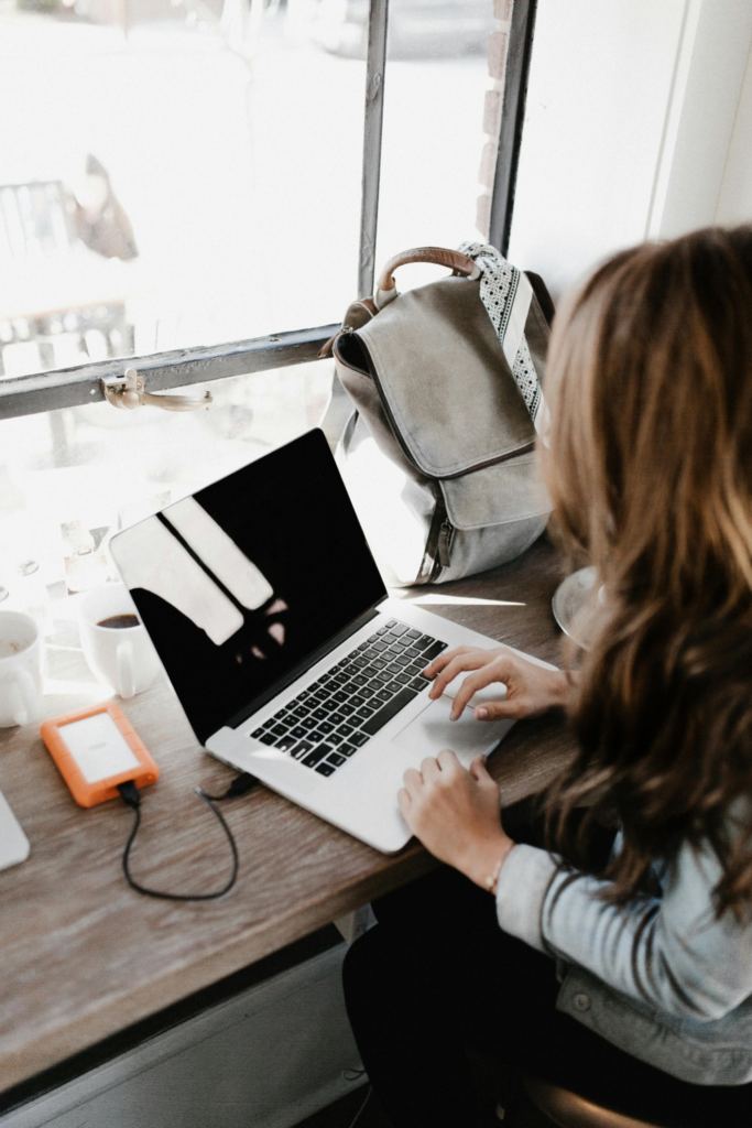 A close-up photograph of a woman sitting beside a table while using a MacBook