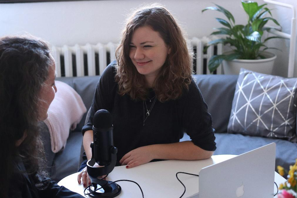 Two women sitting at a desk recording a podcast.