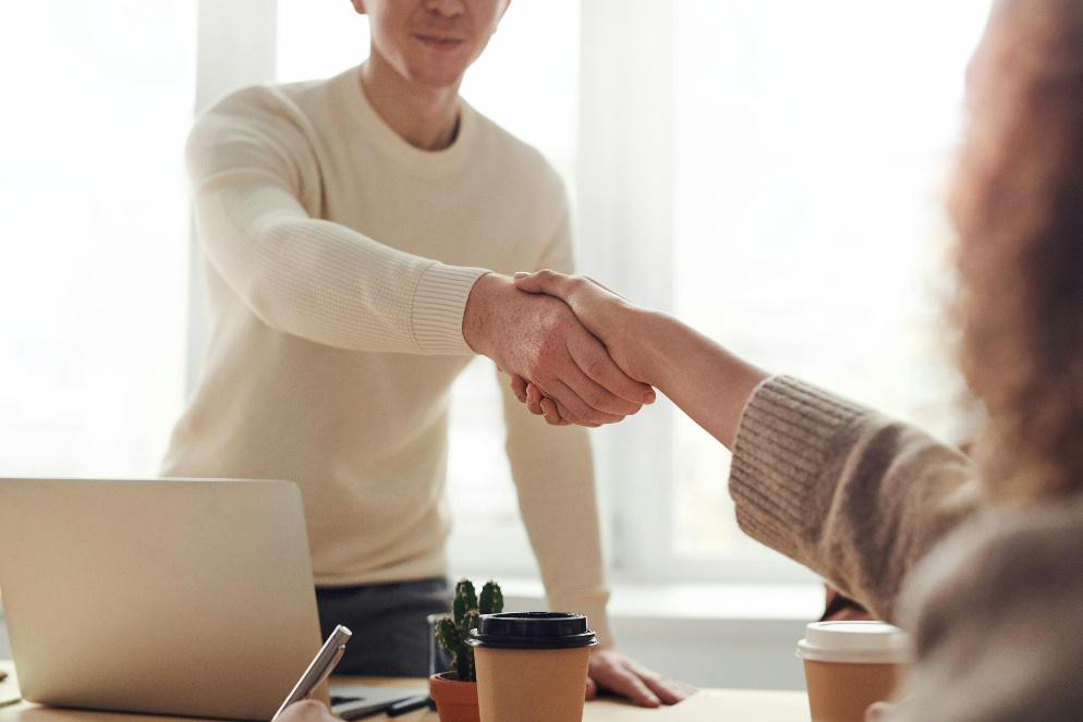 Two people shaking hands in a professional setting, symbolizing partnership and collaboration for nonprofit media placements