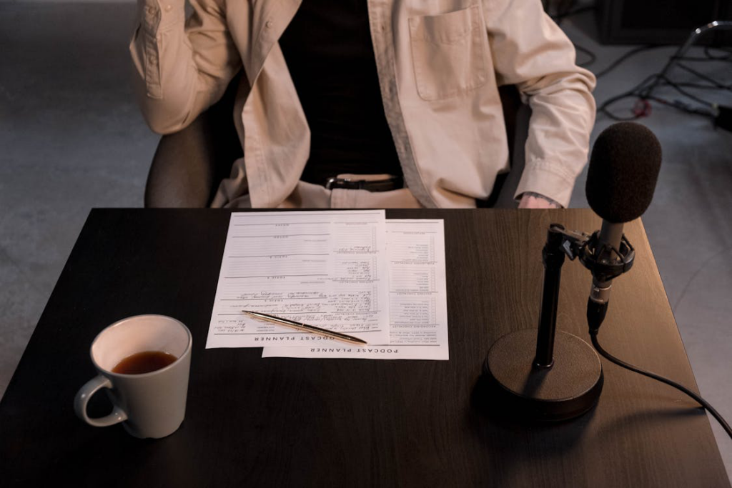person sitting by table with papers and microphone