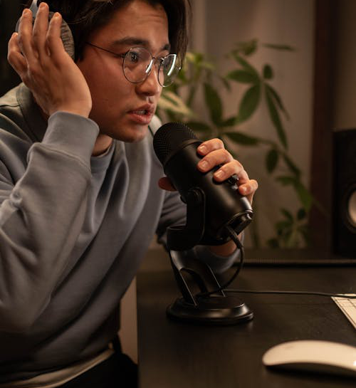 man sitting at the table wearing headphones and talking to the microphone
