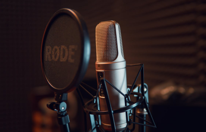 A silver dynamic microphone on a black stand, lit with soft studio lighting.