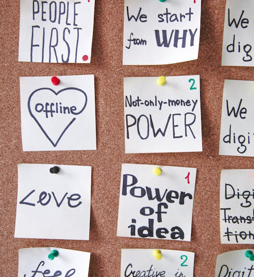 A corkboard covered with sticky notes arranged in a creative, brainstorming-style layout.